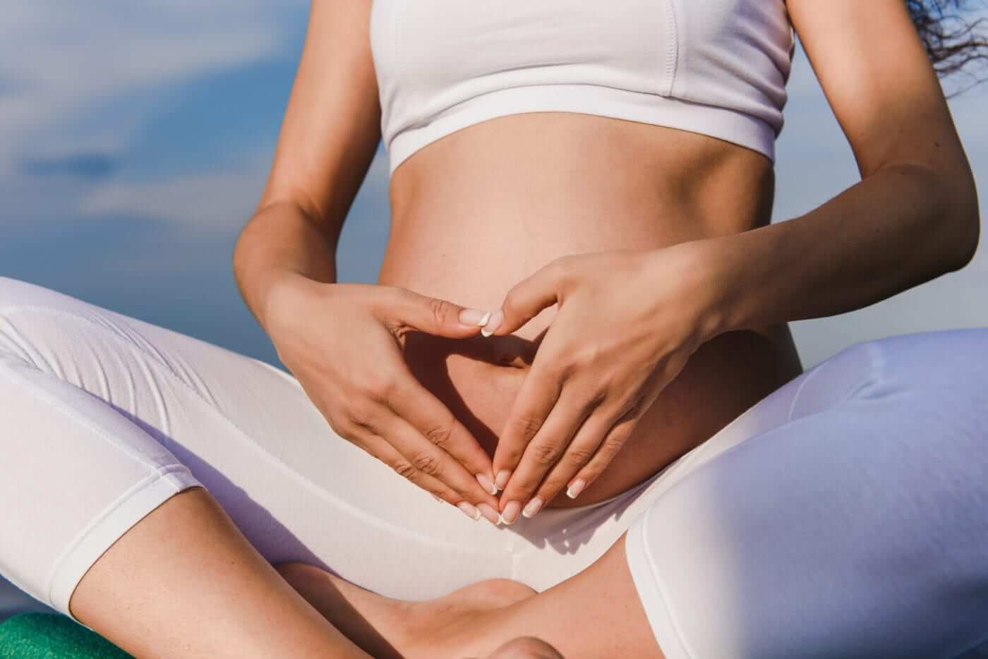 Pregnant woman with hands in heart over tummy for pelvic wellness