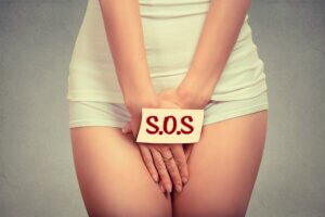 woman holding hand over crotch with sos sign unexpected pelvic pain sos